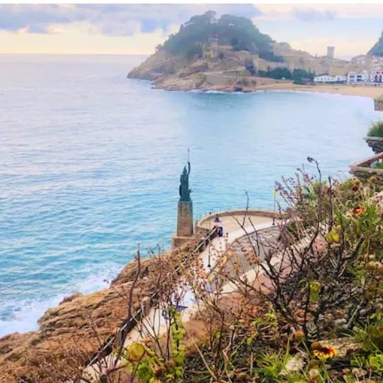 Clifftop path above a turquoise bay and an old walled town